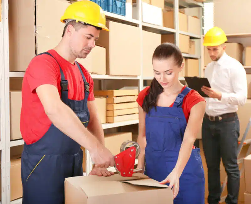 Workers packing and moving boxes in a warehouse.