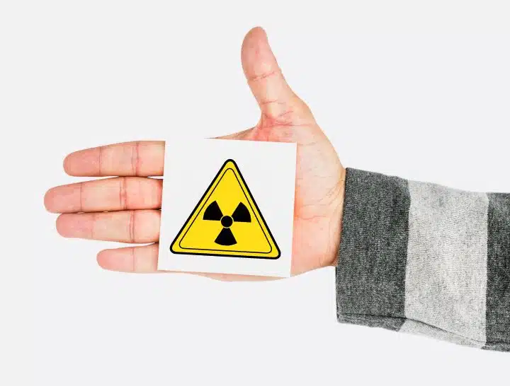 Hand holding radioactive hazard sign.